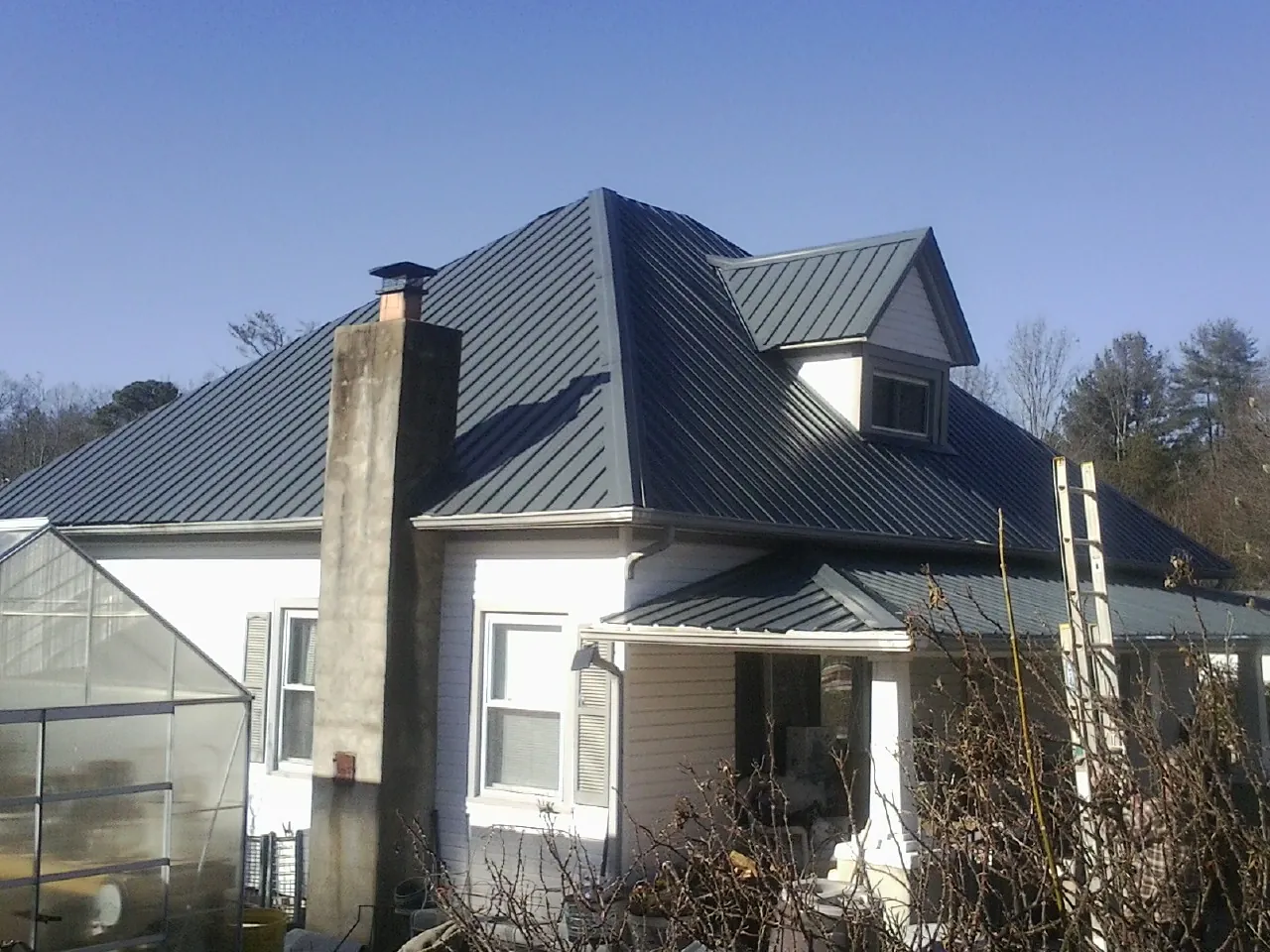 Dark blue standing seam metal roof on a white farmhouse with dormer — Slate & Tile Roof Repair by Roofing Brothers in Shickshinny