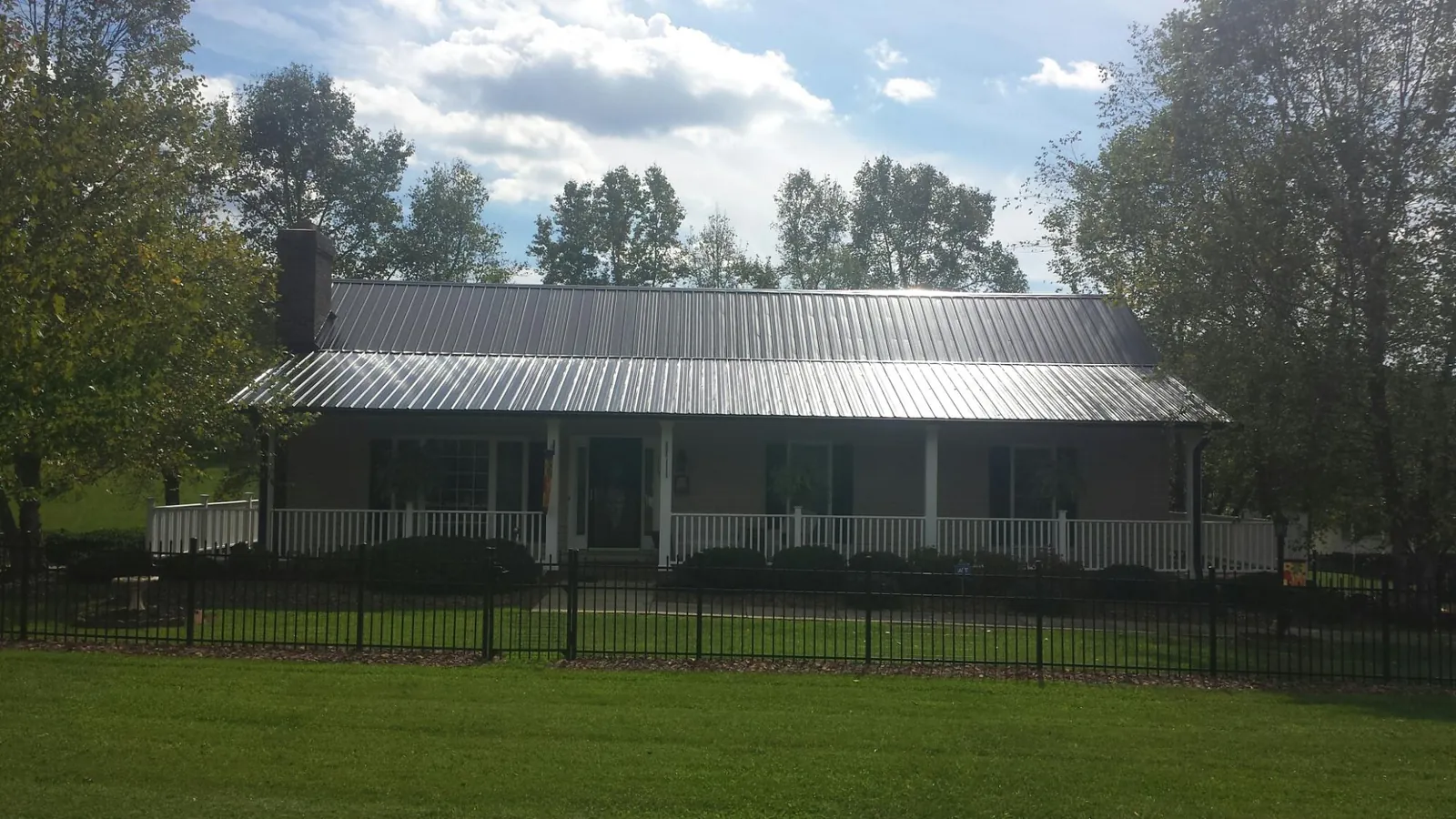 Gray metal roof on a brick ranch with a full width front porch — Gutter Guard Installation work by our crew in Shickshinny