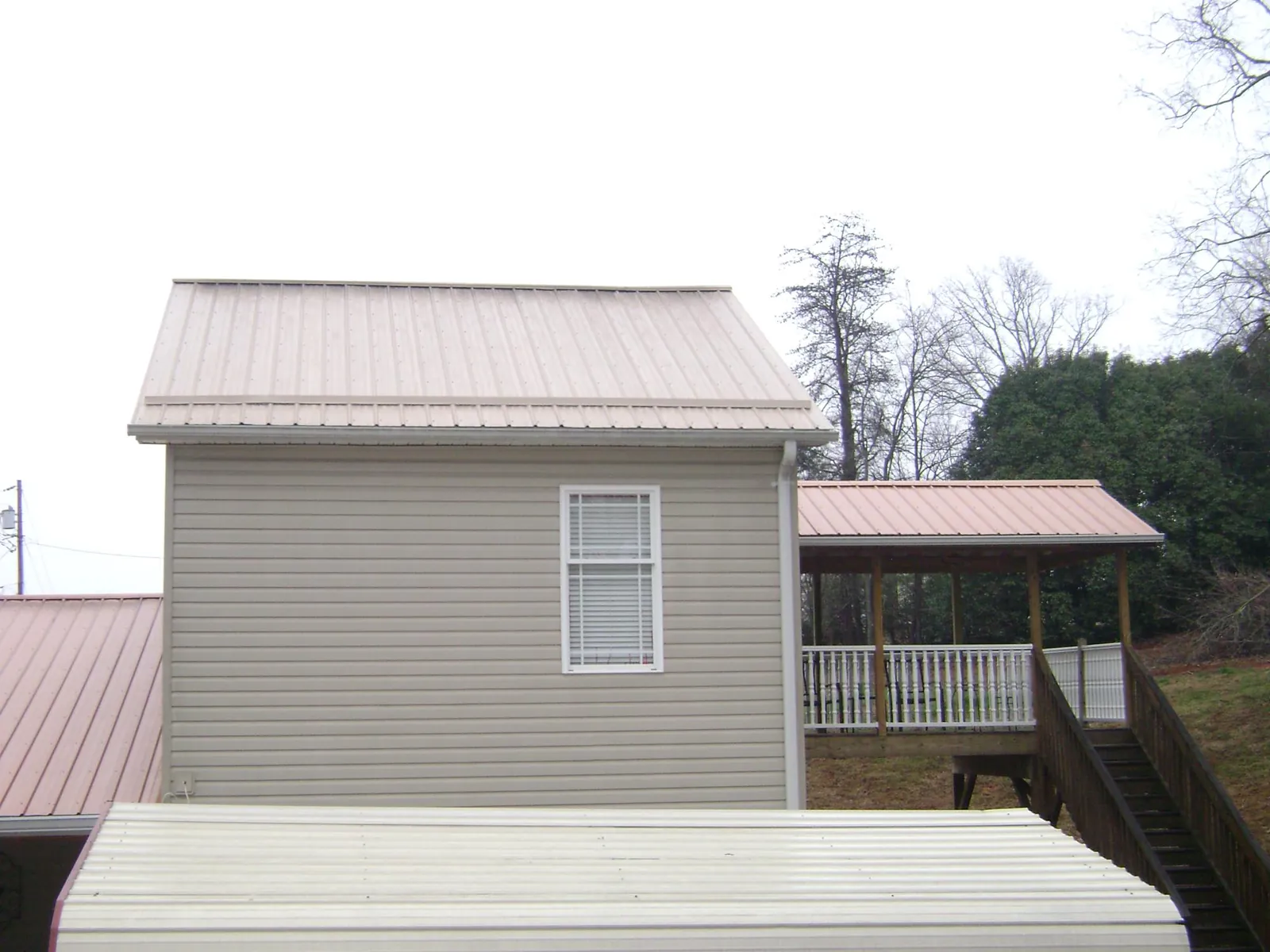 Tan metal roofs on a two story addition and attached porch, from a Roof Replacement job in Shickshinny