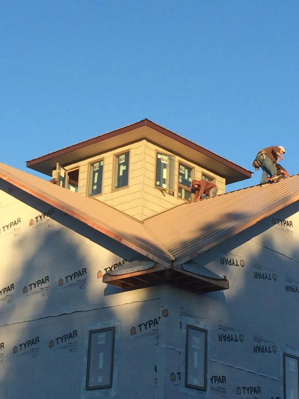 Roofers working around a rooftop cupola on a new metal roof at sunset — Roof Waterproofing in Shickshinny by Roofing Brothers